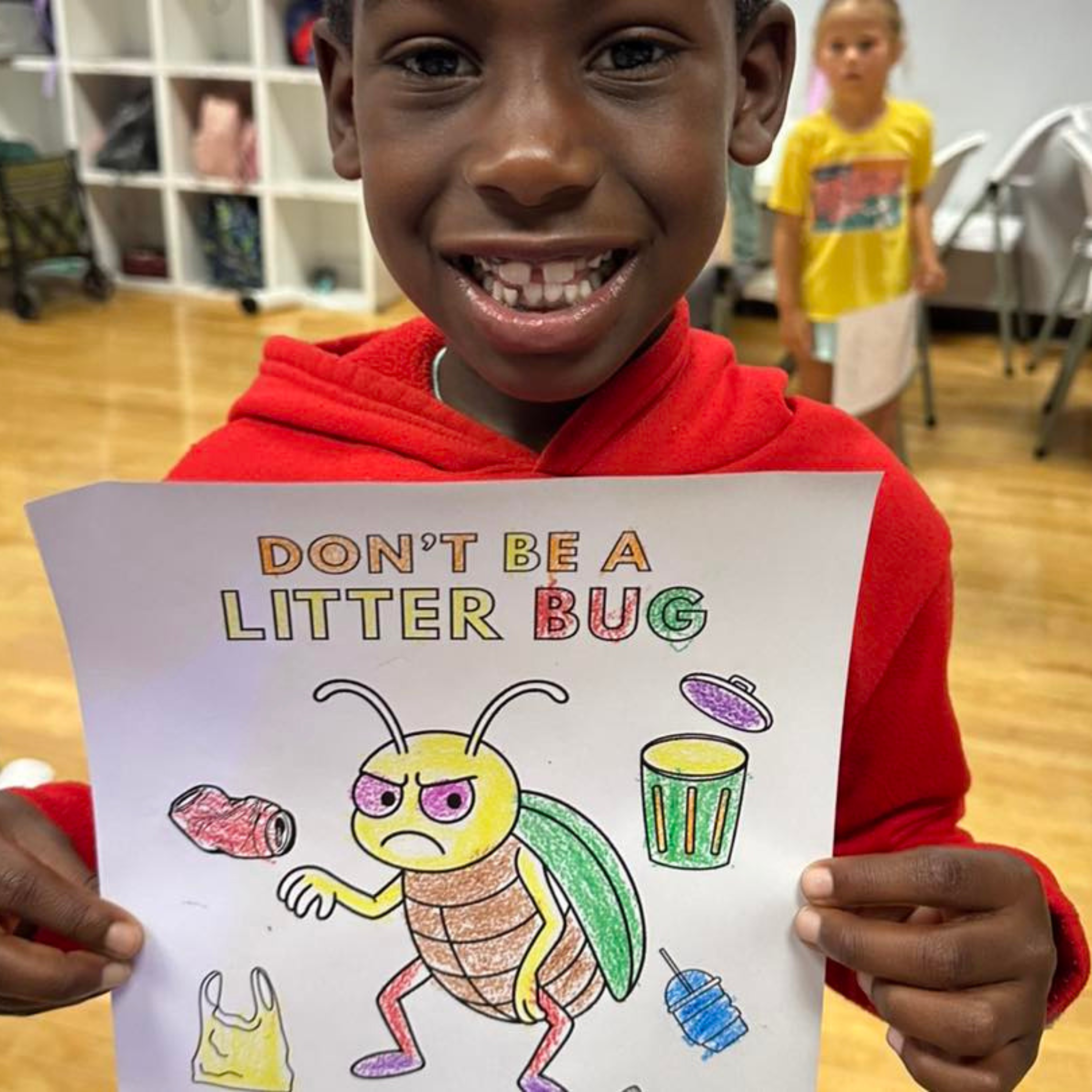 Young boy holding up coloring book page with title "Don't Be a Litterbug" with cartoon illustration of a grumpy beetle.